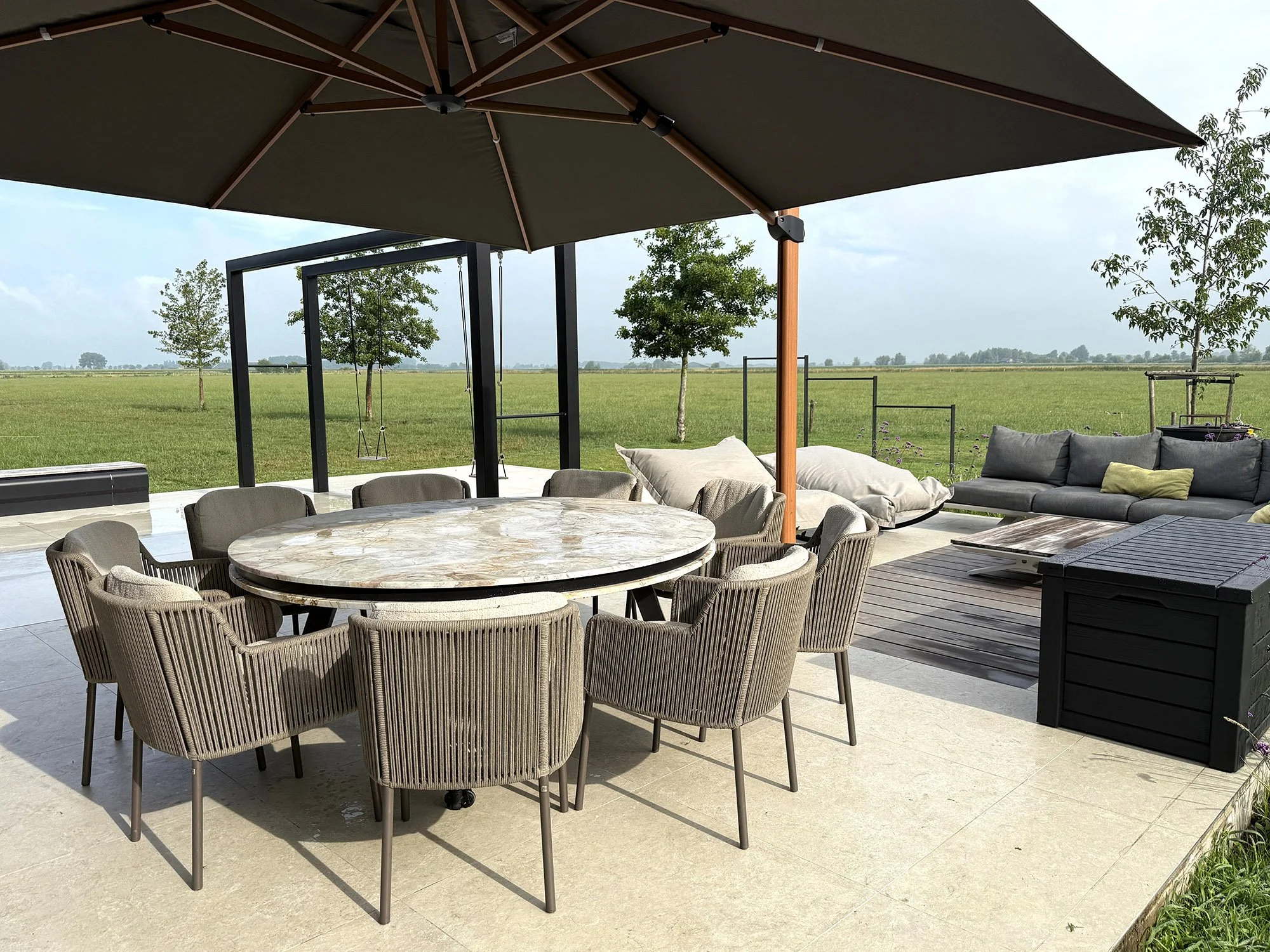 terras met parasol en grote ronde marmeren tafel