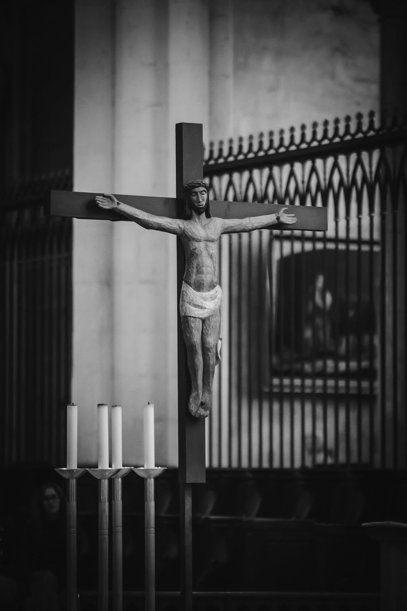 Statue de Jésus crucifié dans une église, en noir et blanc, avec des bougies à côté.