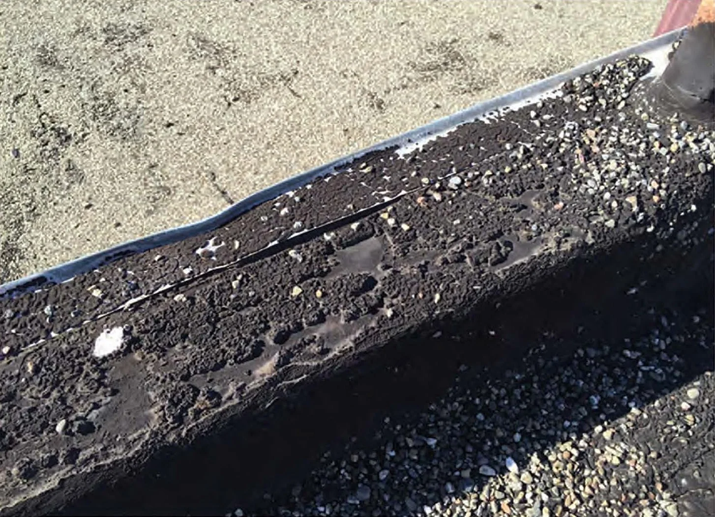 "Deteriorated 15-year-old tar and gravel roof in San Francisco showing eroded gravel and exposed tar membrane"