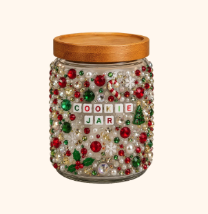 Glass jar filled with Christmas-themed decorative beads and sequins, labeled 'COOLONE JAR' with a small Christmas tree decoration on the right, topped with a wooden lid.