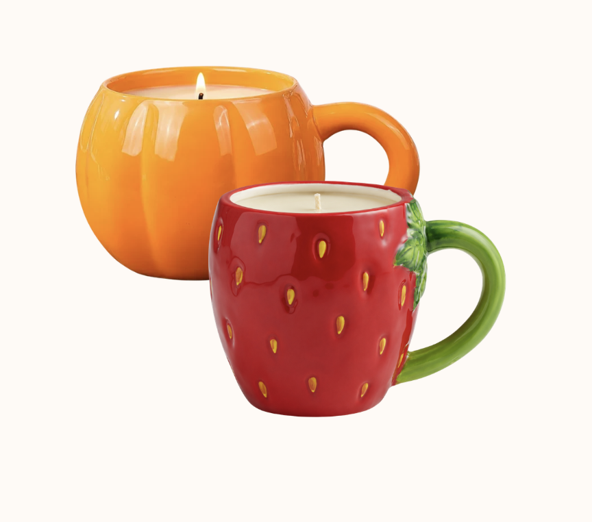 Two colorful strawberry-themed mugs with candles inside, one shaped like a strawberry and the other like a pumpkin.