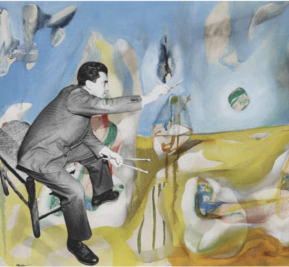 A black-and-white photo of a man in a suit sitting on a chair, holding paintbrushes, and interacting with an abstract colorful painted background. The man appears to be mimicking painting or conducting in front of the abstract art.