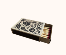 A decorative matchbox with a floral pattern on the lid, partially open to reveal matches inside.