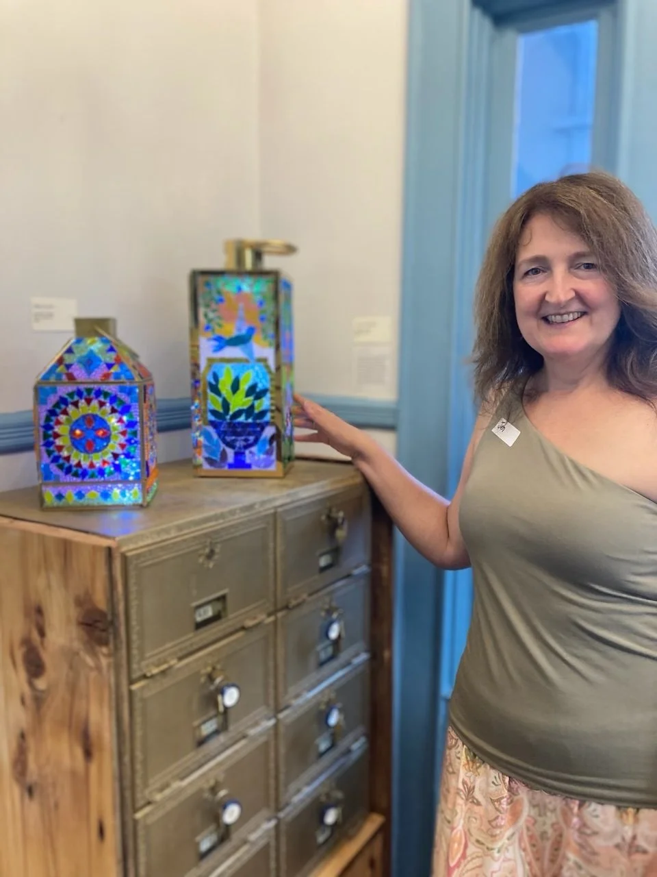 A woman standing next to two glass mosaic lamps.jpg