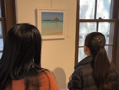 Two women look at a painting of an umberlla on a beach