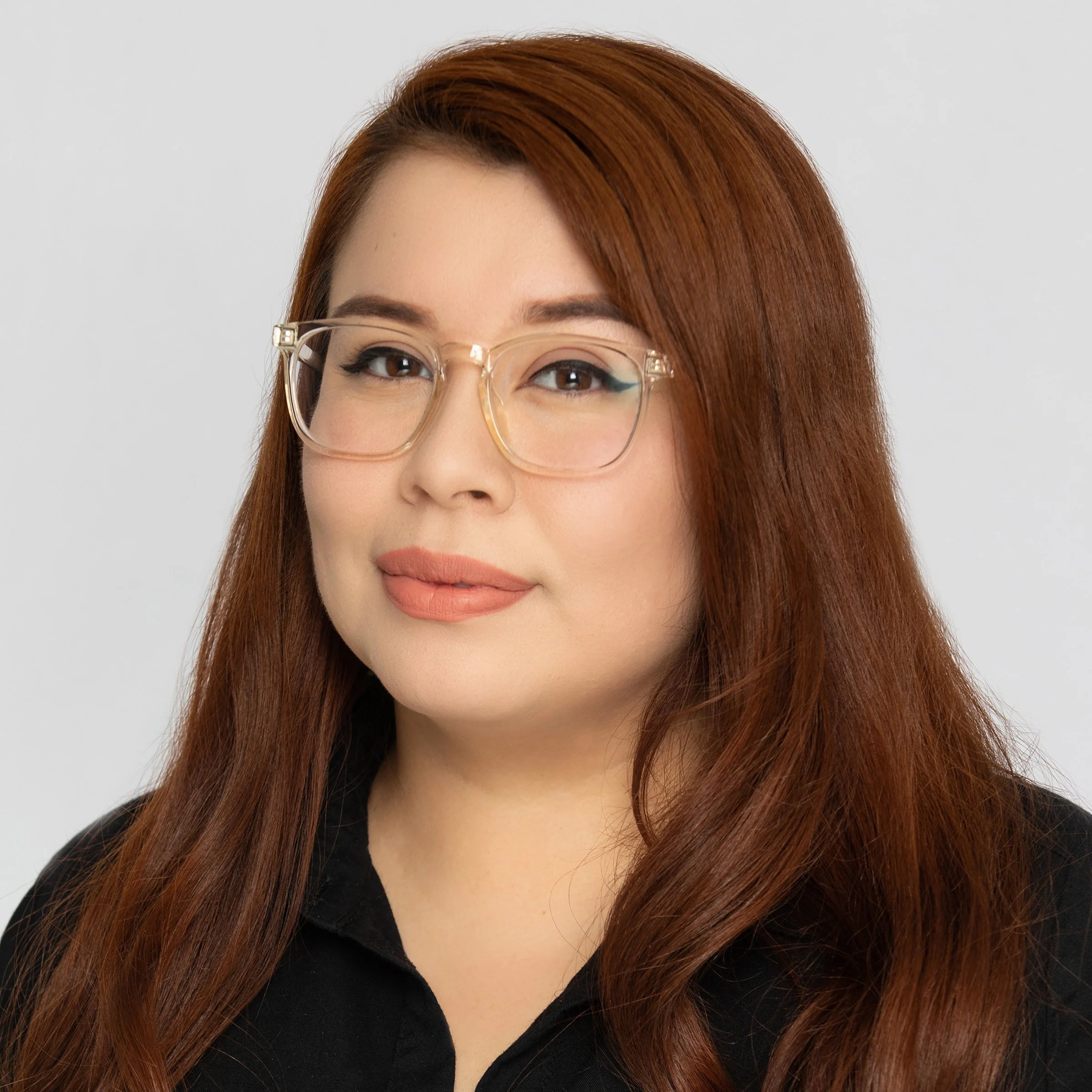 A woman with dark red hair wearing glasses with a black top.