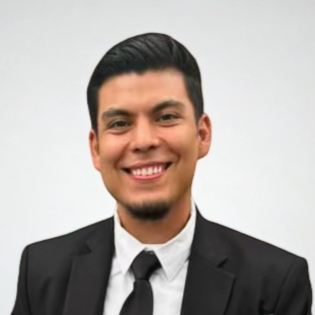 Smiling man with short black hair wearing black suite and tie.