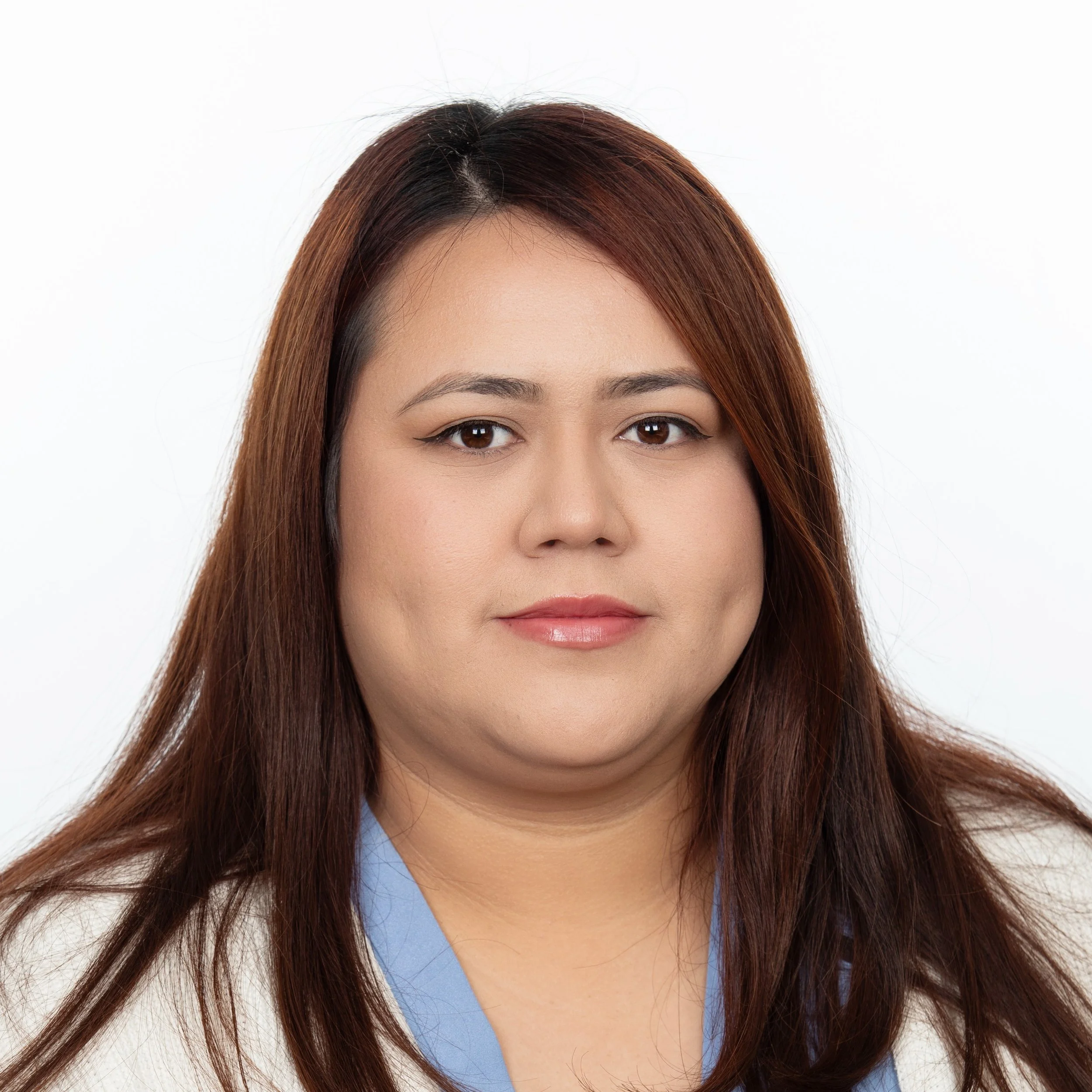 Smiling woman with long straight red-brown hair wearing a light blue blouse.