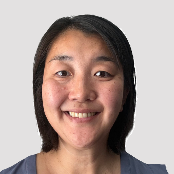 Smiling woman with medium length black hair wearing a blue blouse.