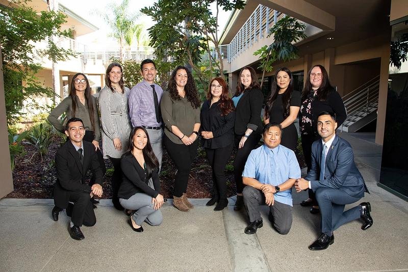 IRI management team smiling while standing and kneeling in professional attire.