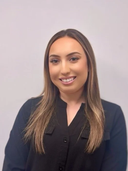Smiling woman with long light brown hair wearing a black top.