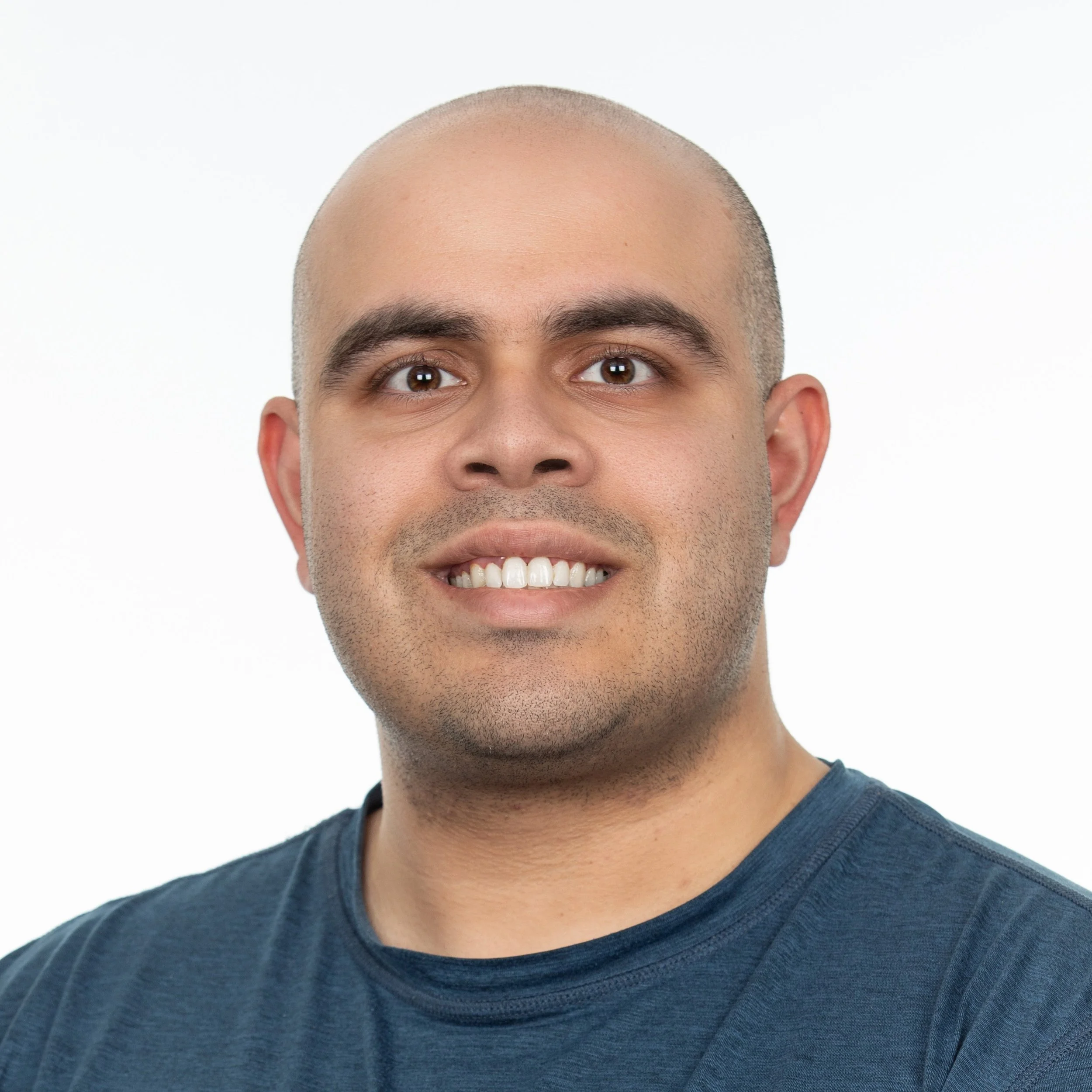 Smiling man wearing a blue crew neck t-shirt.