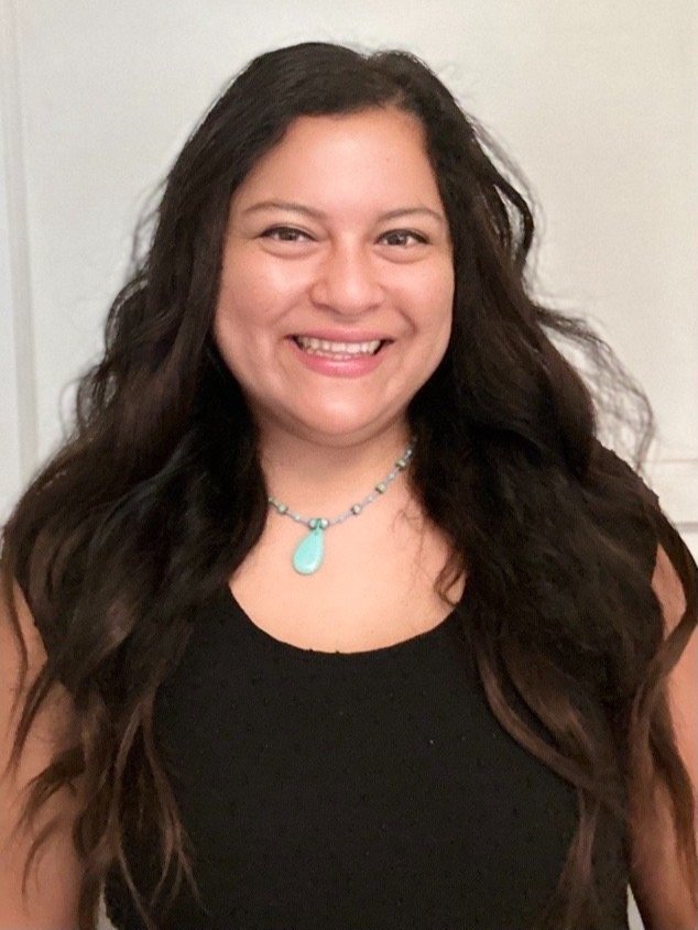 Smiling woman with dark brown hair wearing a black shirt with a turquoise necklace.