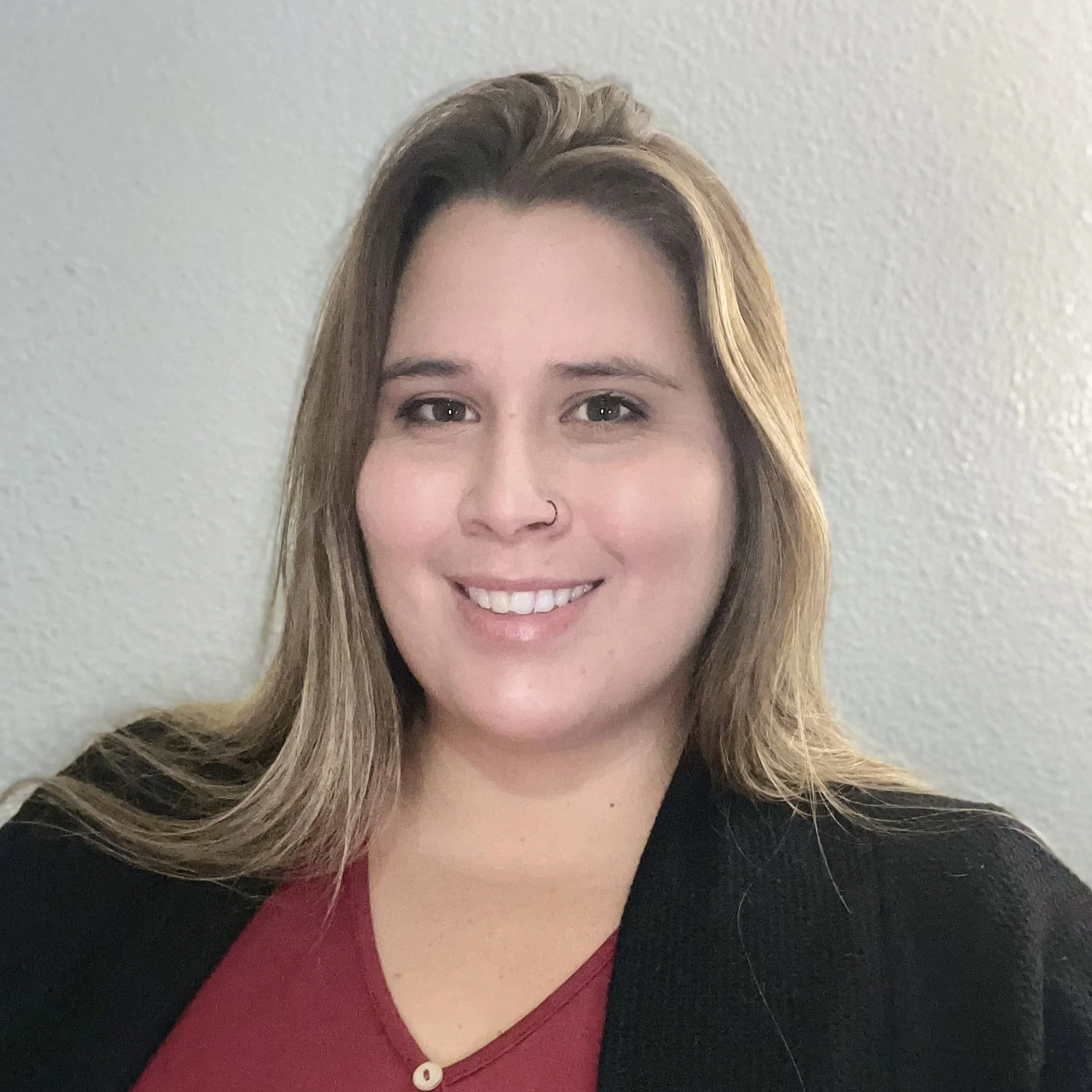 Smiling woman with long blonde hair wearing a red shirt and black blazer.