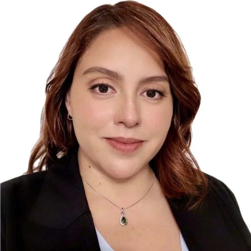 Smiling woman with long red-brown hair wearing a necklace and black blazer.