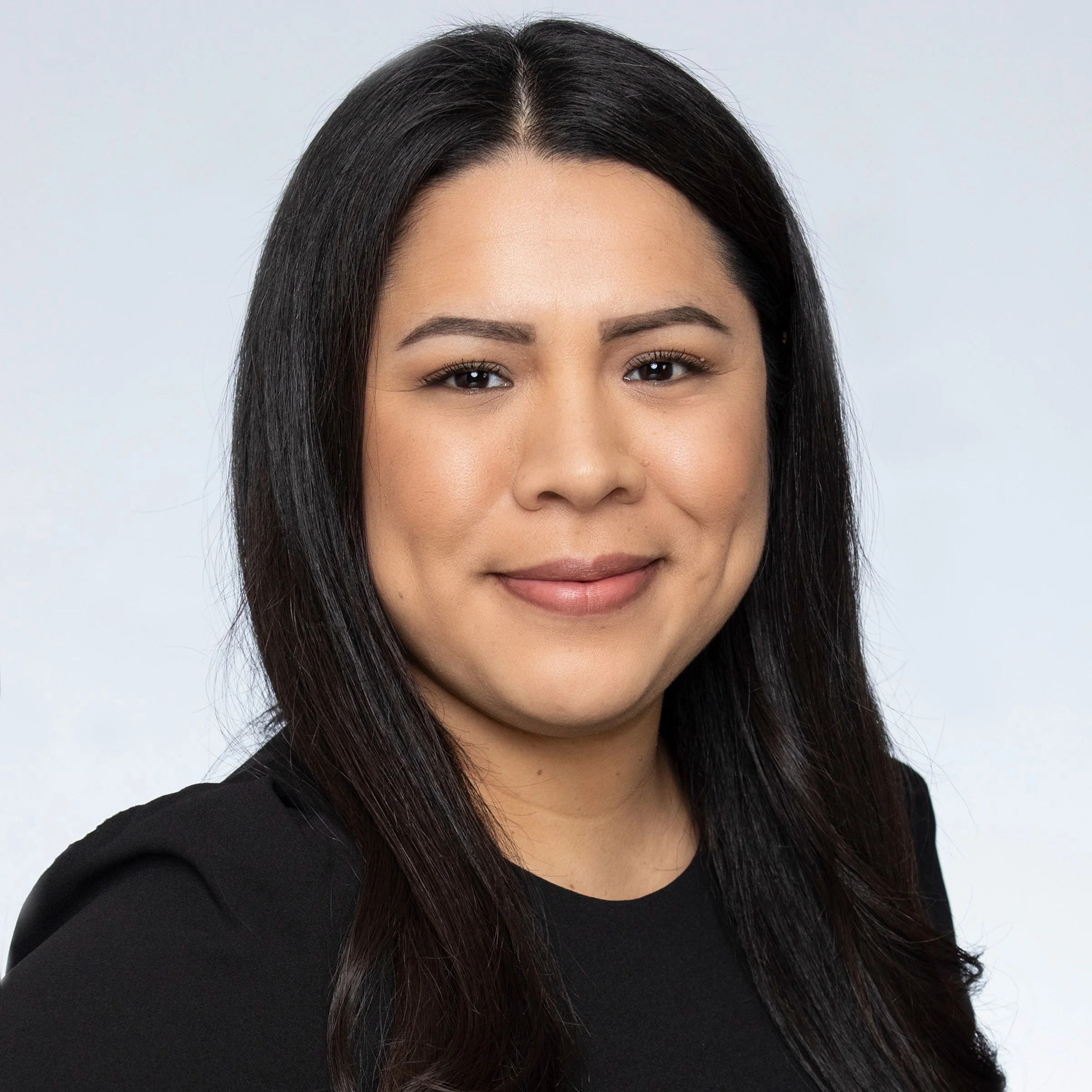 A woman with long dark straight hair wearing a black top.