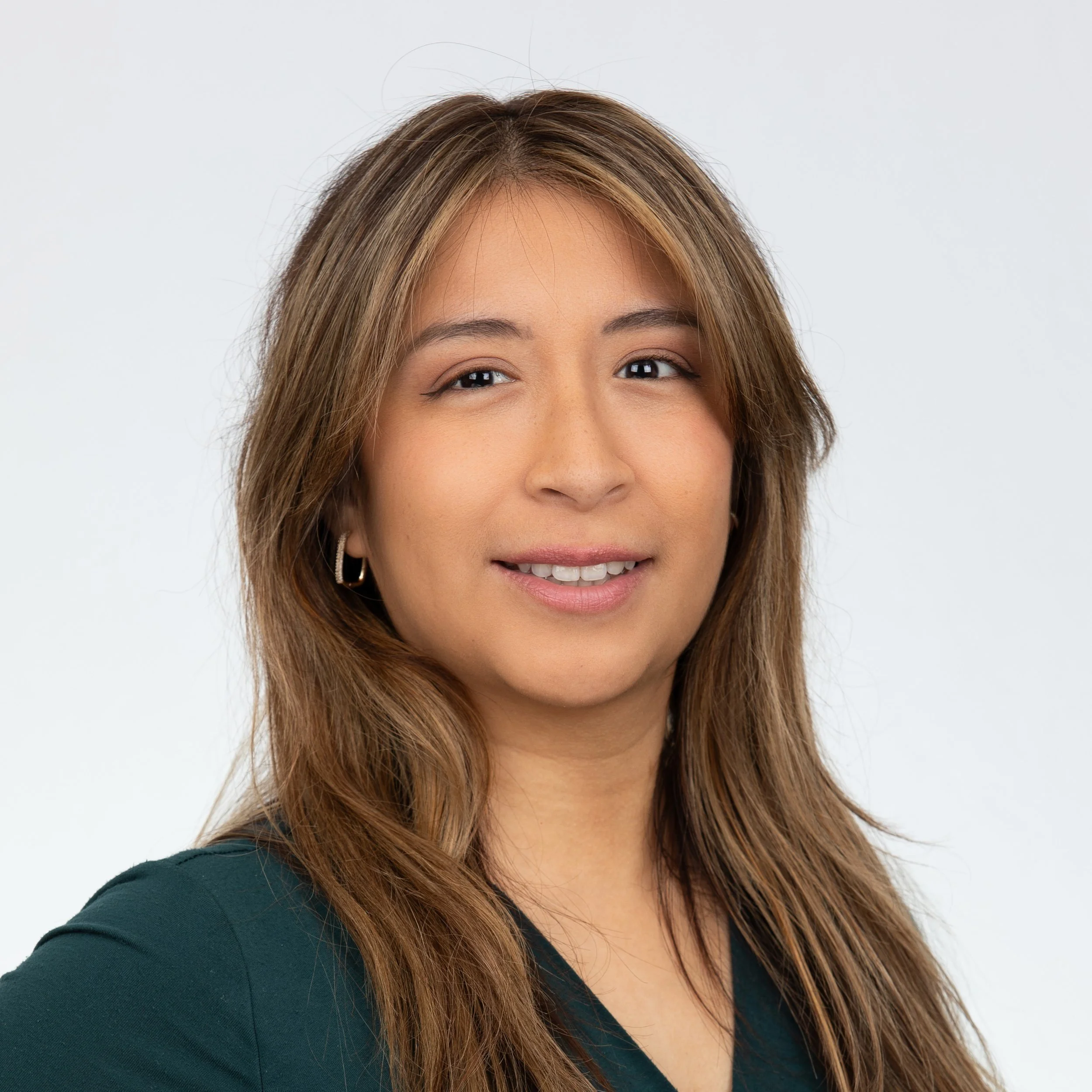 A woman smiling with light brown long hair in a green blouse.