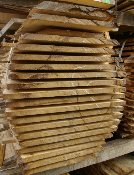 Close-up of a wooden plank with a vibrant, striped grain pattern, held by a hand with purple dye on fingers.