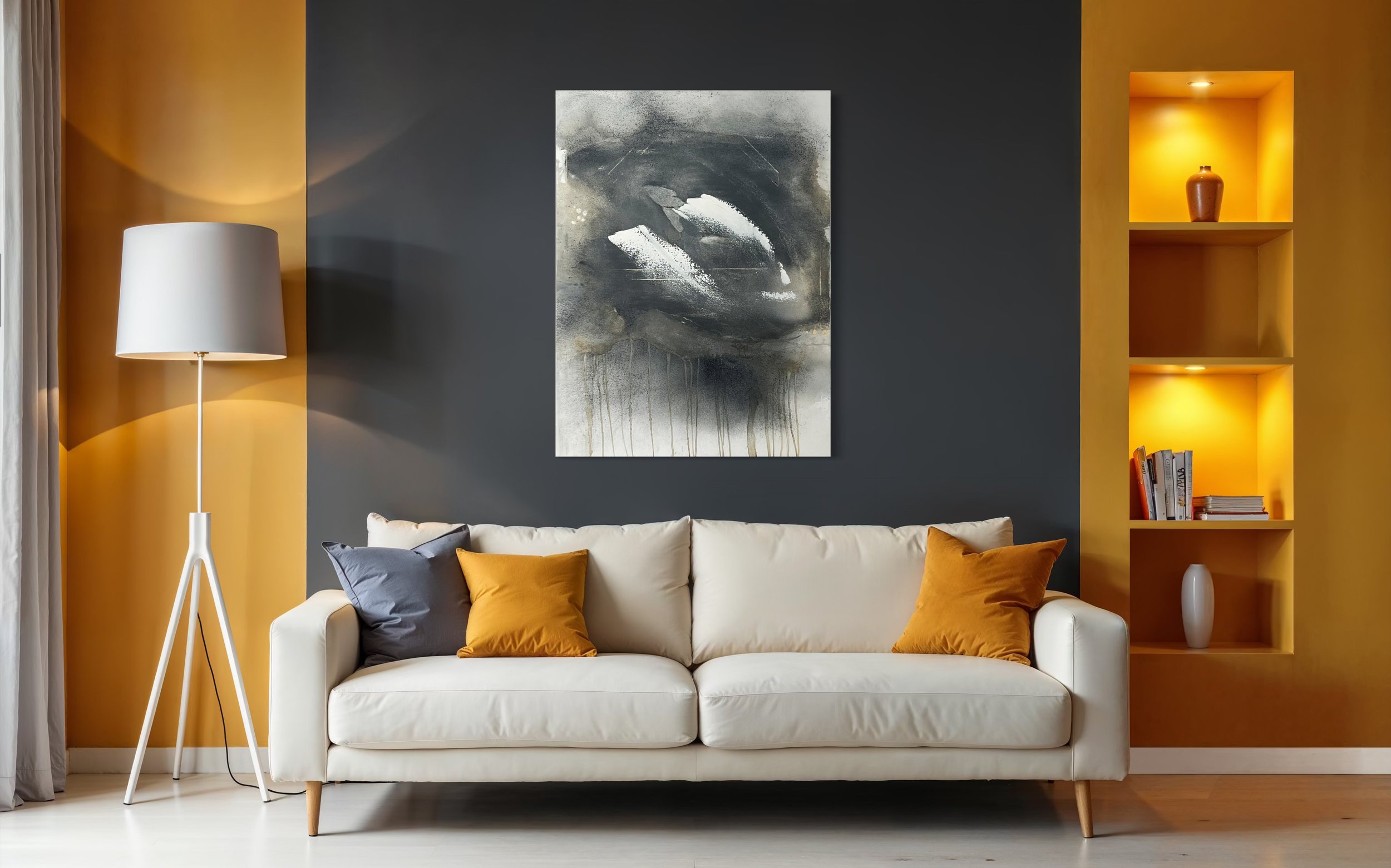 Living room with a white sofa, mustard yellow and gray throw pillows, a tall lampshade, black and white abstract art on a dark gray wall, and a yellow built-in shelving unit with a vase and books.