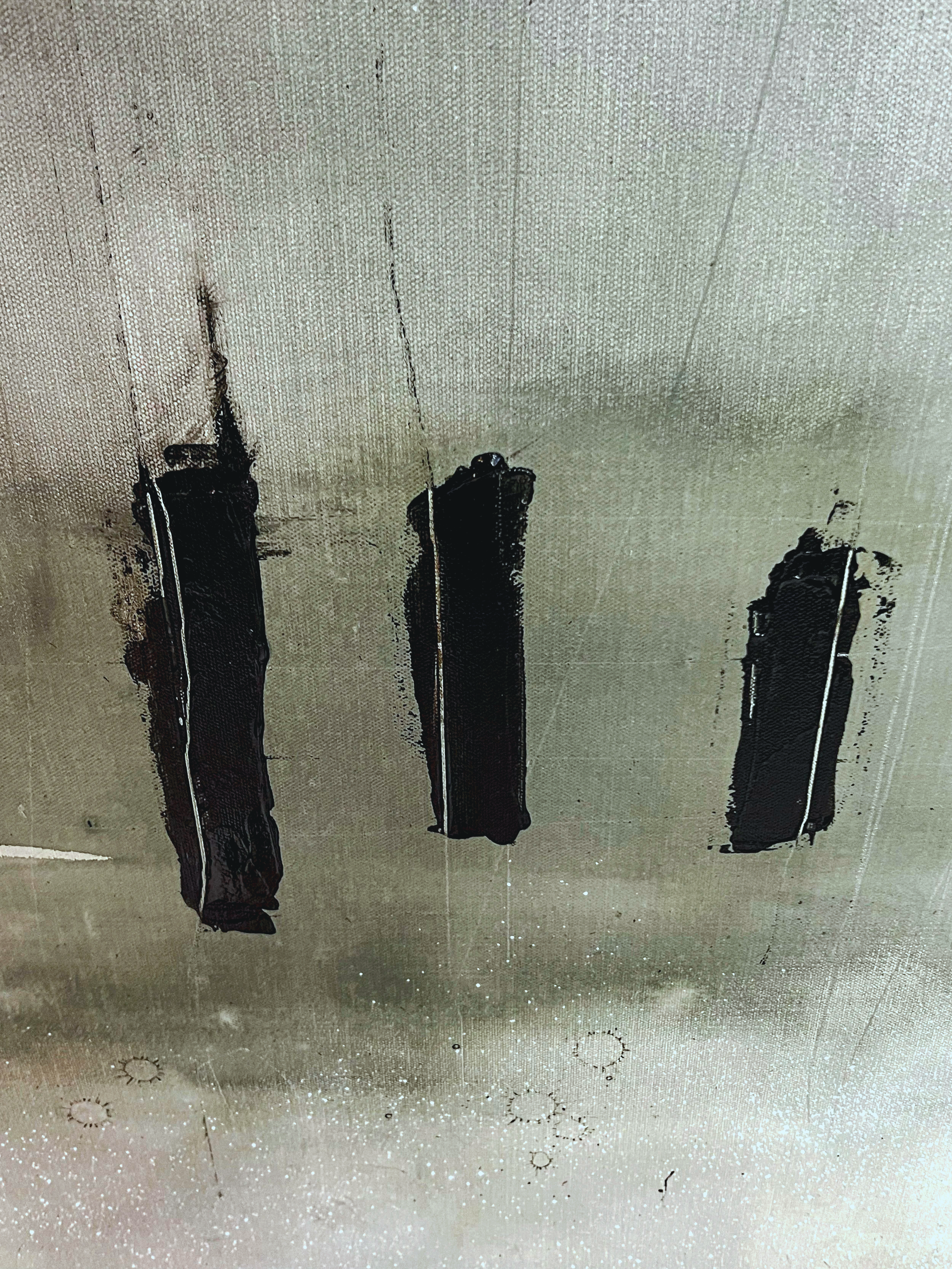 Three black spray paint cans with caps, upside down on a stained light-colored ceiling with visible dirt and circular markings.