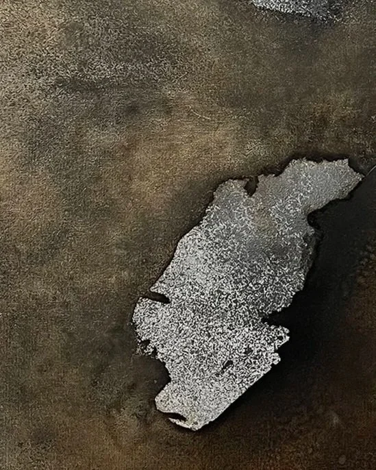 A textured, dark surface with a peeling patch of silver metallic paint.
