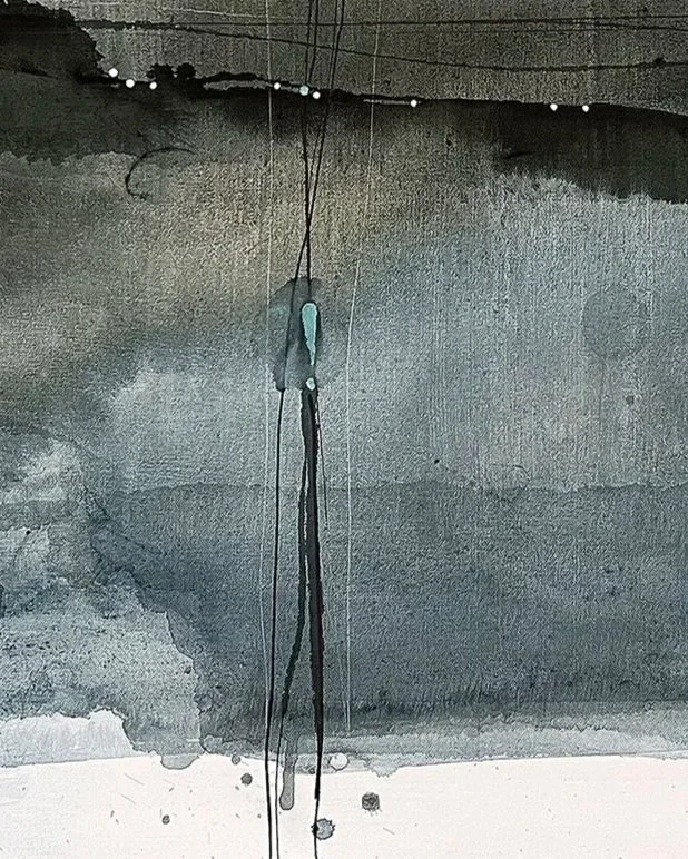 A close-up of a wall with black and gray paint streaks and drips, with some visible drywall texture and punctures.