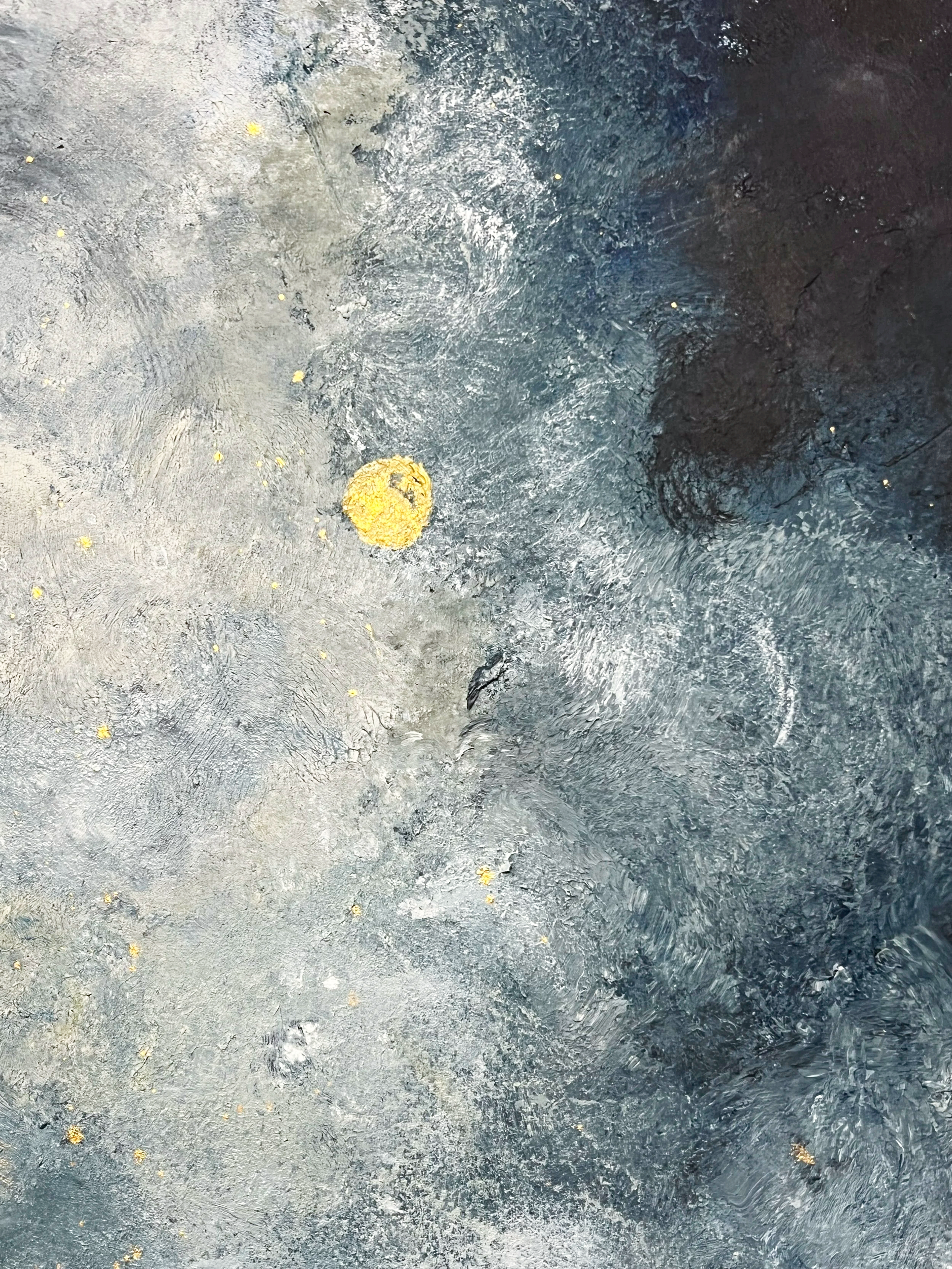 Close-up of a textured metallic surface with scattered small yellow and gold flecks and a few rounded yellowish objects on it.