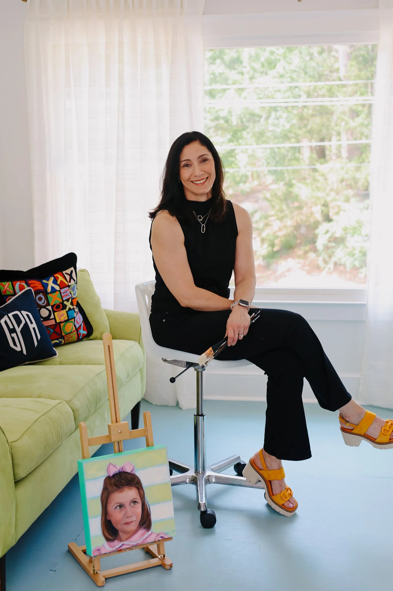 Professional artist Libbie Patterson painting custom acrylic portraits in her art studio, surrounded by finished child and pet portrait commissions.