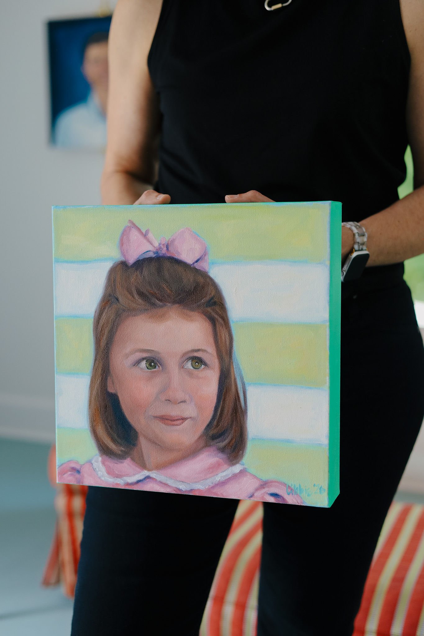 Artist Libbie Patterson holding a completed custom acrylic child portrait in her studio, showcasing a personalized portrait commission by Studio LKP.