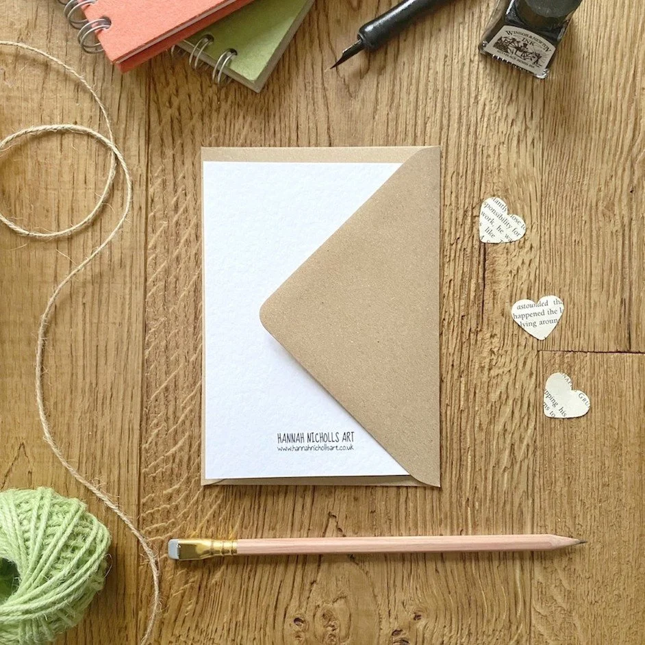 flat lay desk photo of reverse of greeting card with Hannah Nicholls Art logo