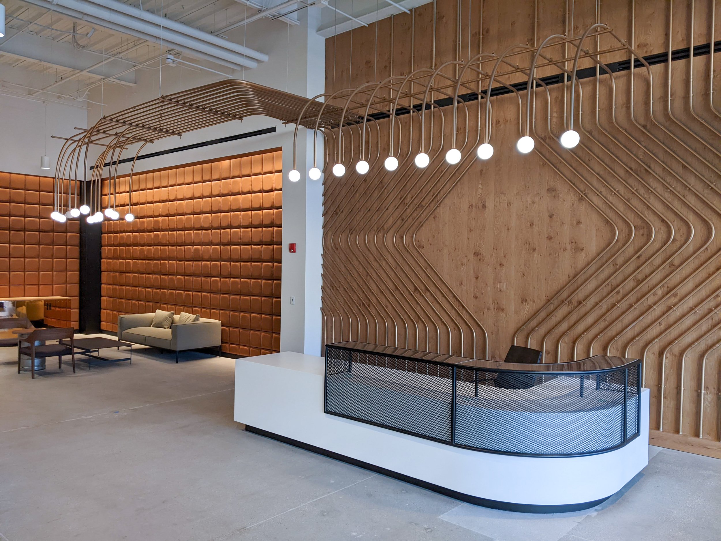 Steel transaction shroud for reception desk: curved flat bar frame + expanded metal infill + matte black powdercoat