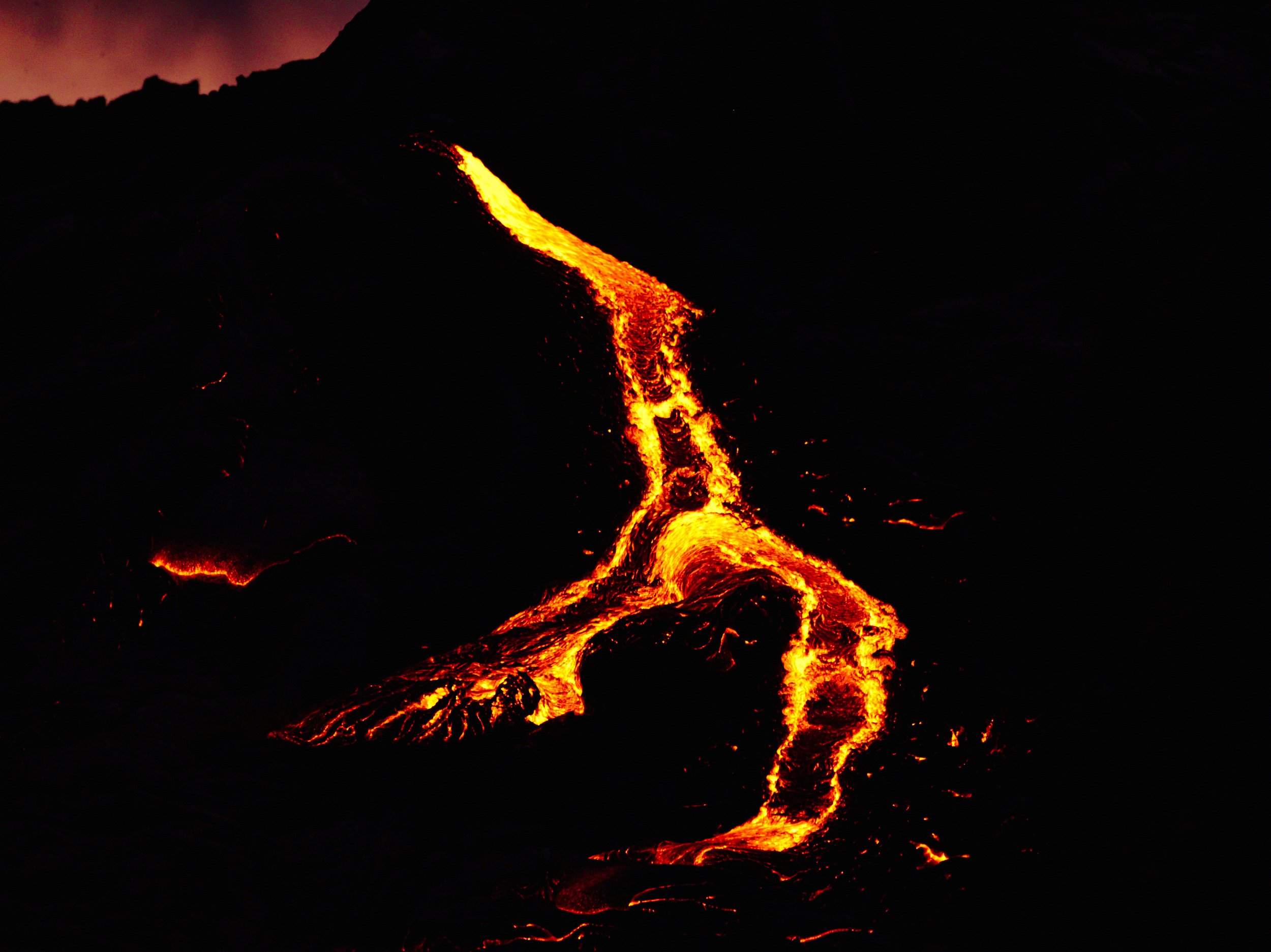 Flowing lava from an erupting volcano in the dark night.