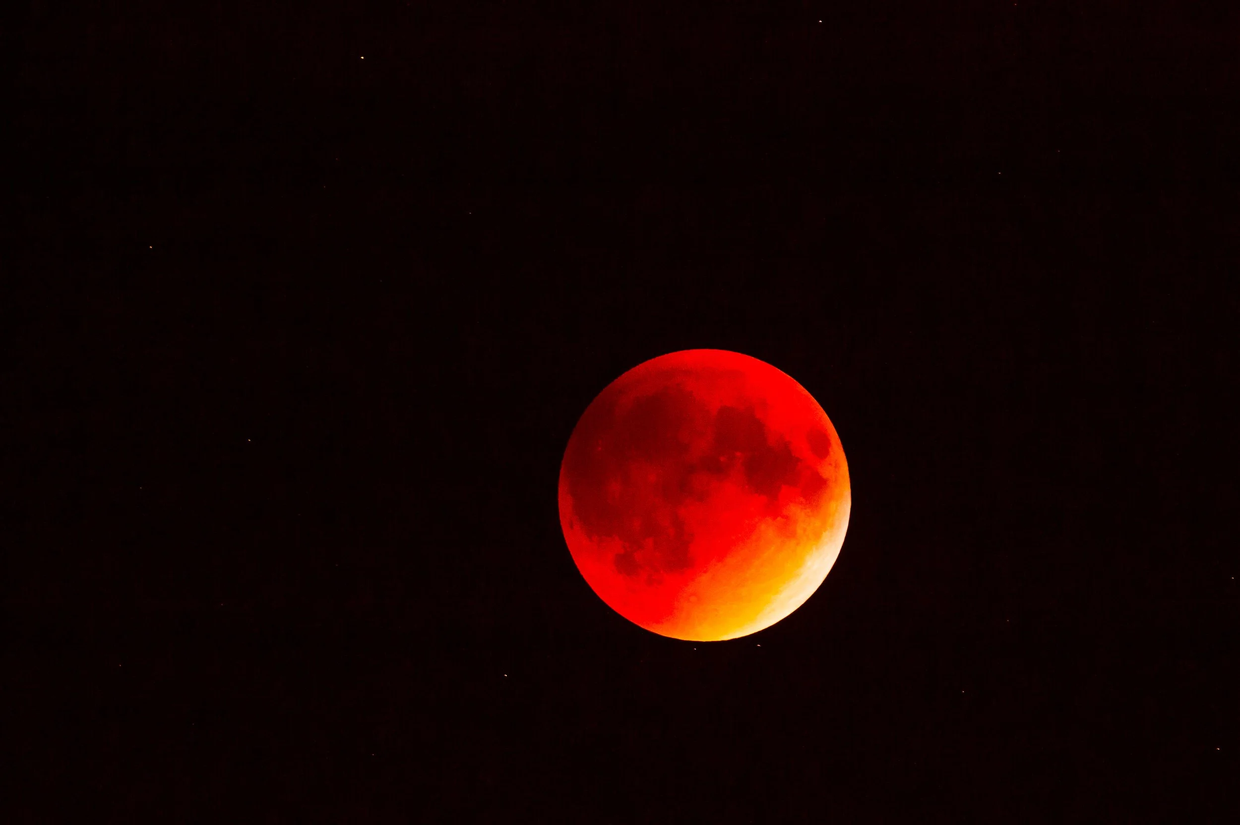 A blood-red lunar eclipse cast on the moon with a dark sky background.