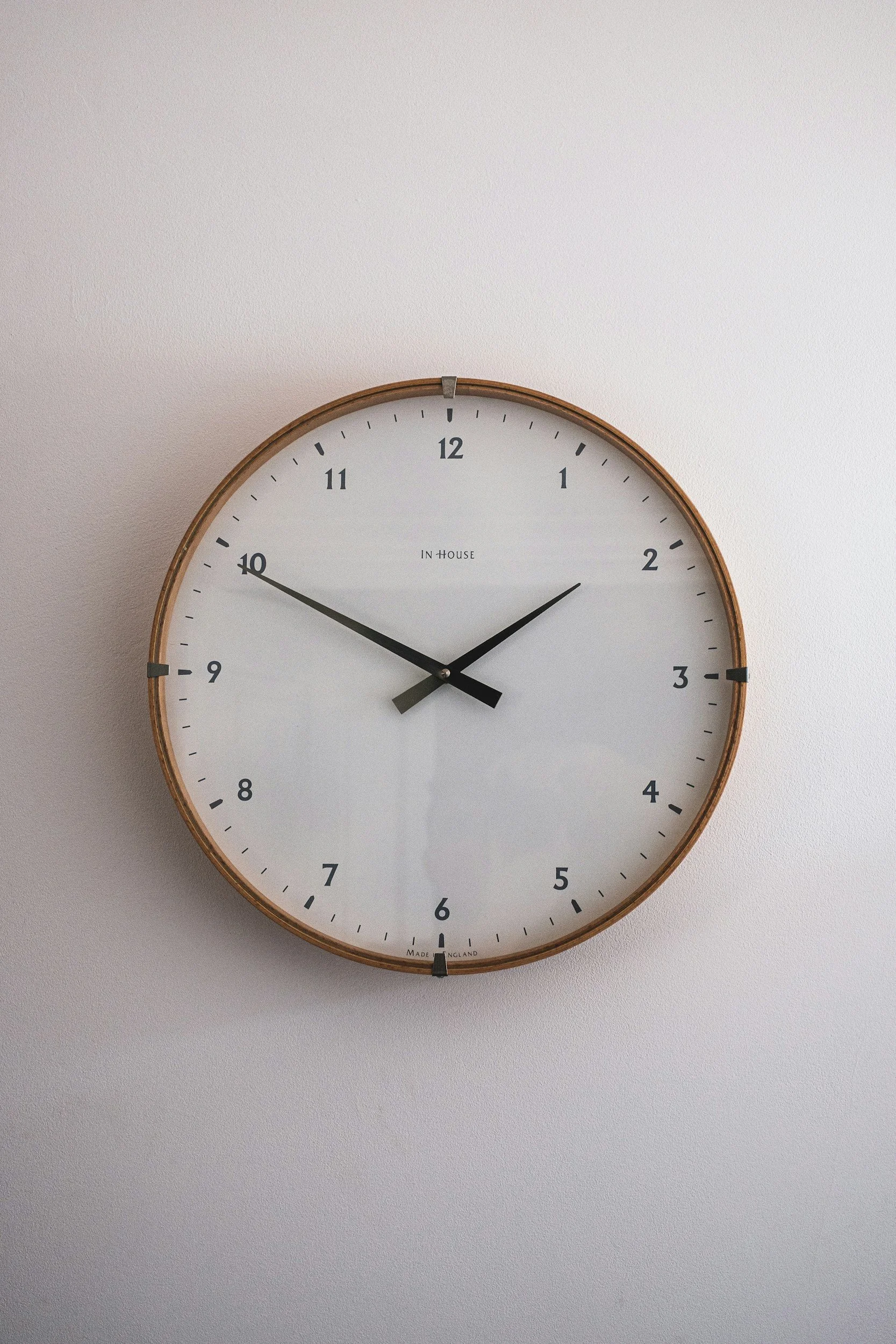A round wall clock with black hands, showing the time as approximately 2:49, hanging on a light-colored wall.