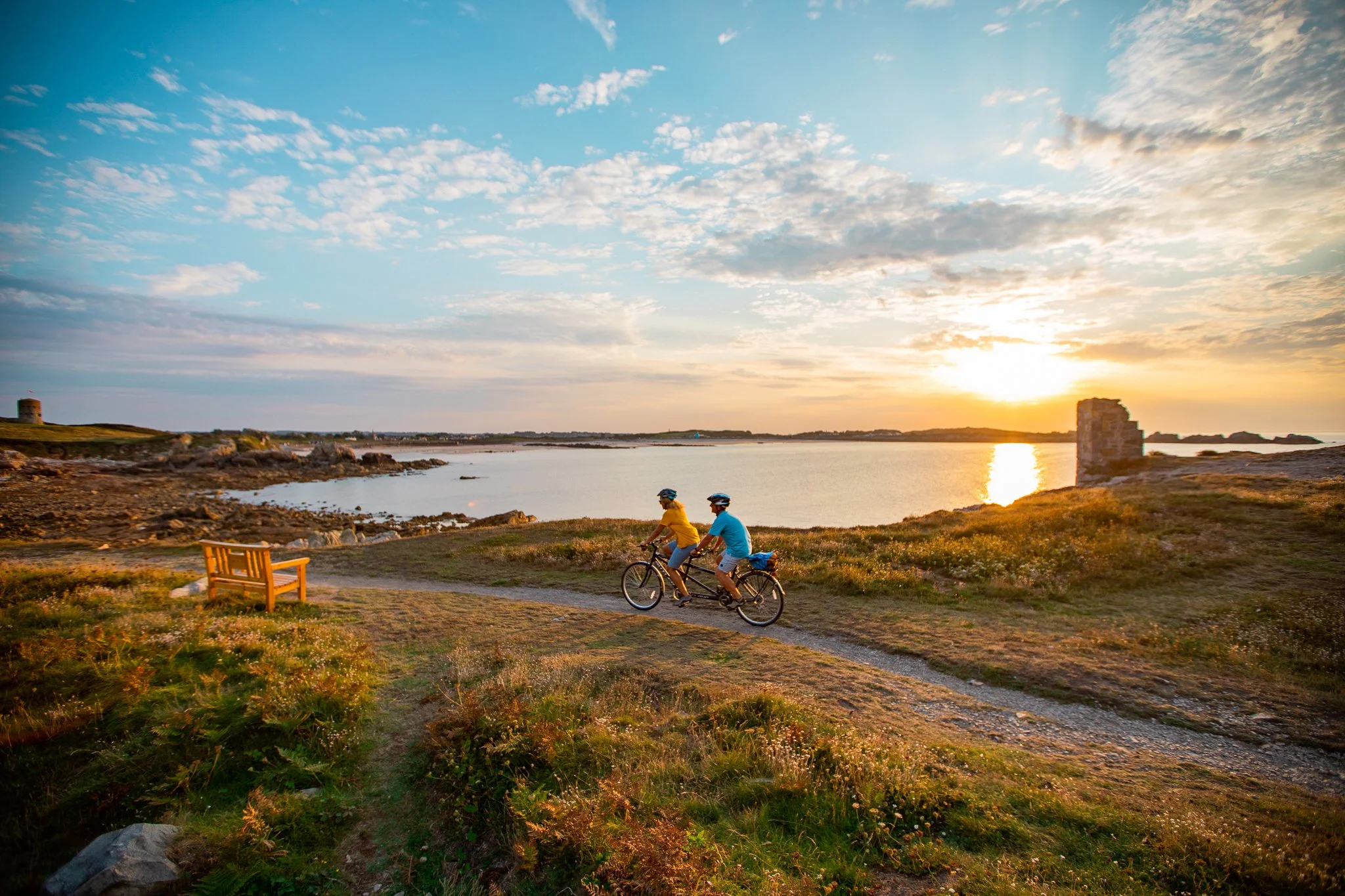 People riding bikes along L'Ancresse common path at sunset, Guernsey