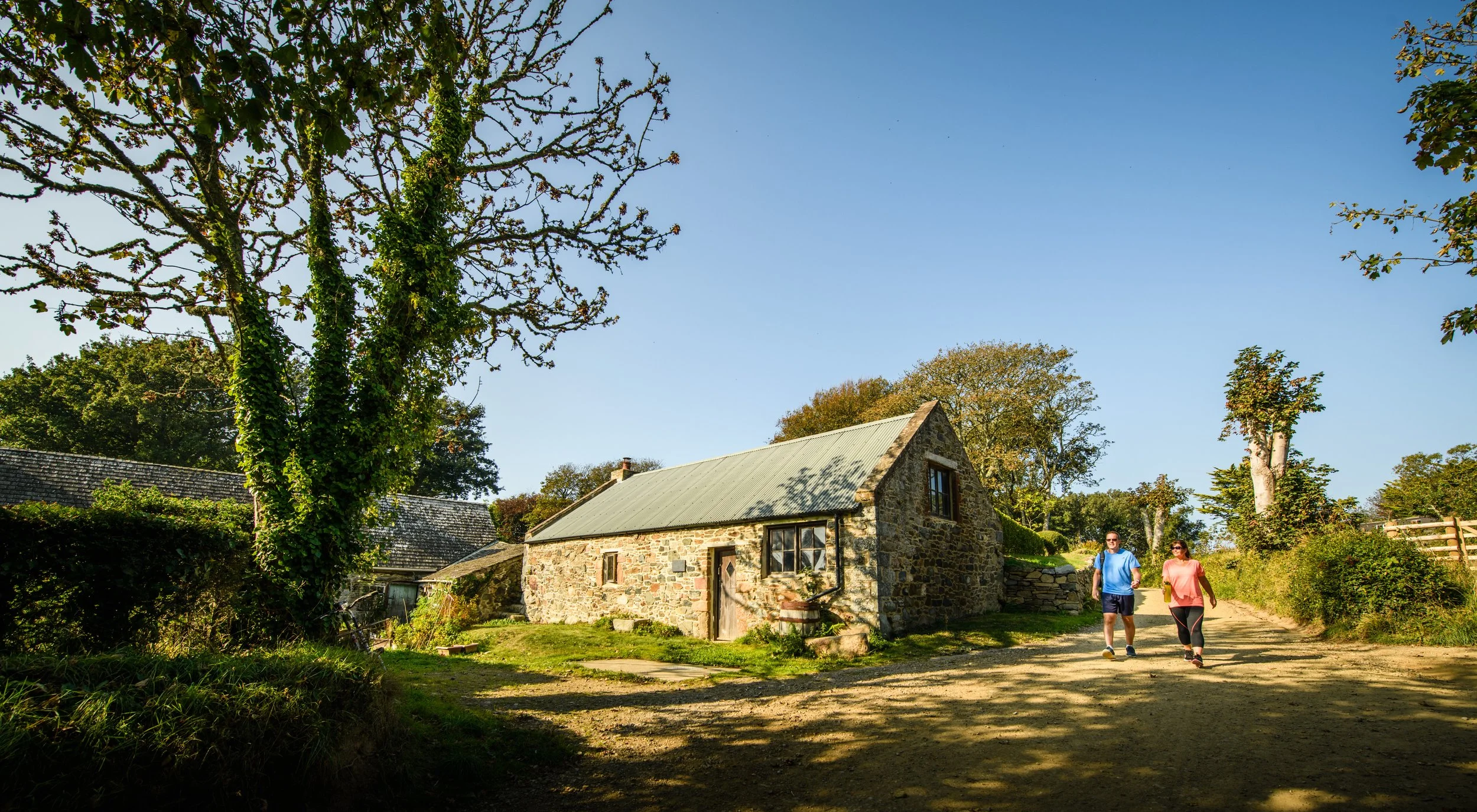 Visitors walking past granite building on Sark during guided island tour