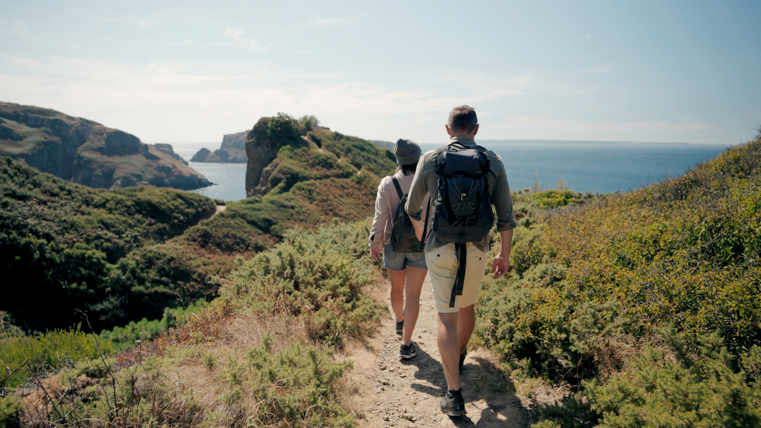 Couple walking along cliff tops on Sark Island with panoramic sea views