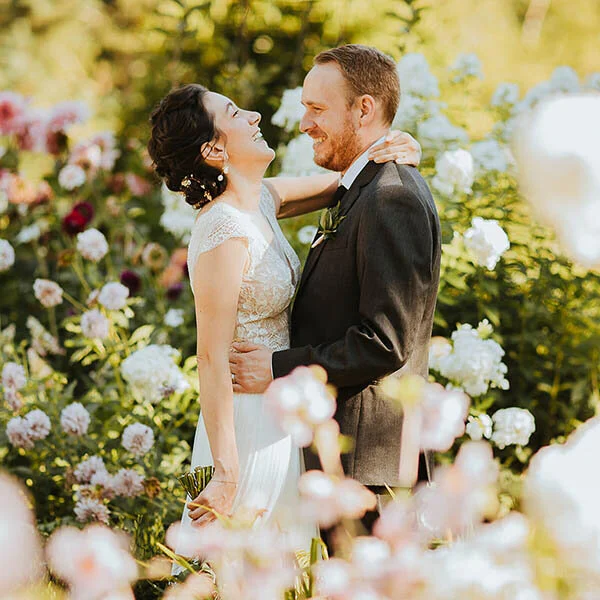 Bride and groom laughing in a field of flowers at Twin Willow Gardens