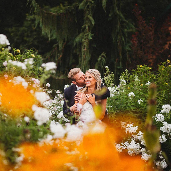 Bride and groom laughing in a field of flowers at Twin Willow Gardens