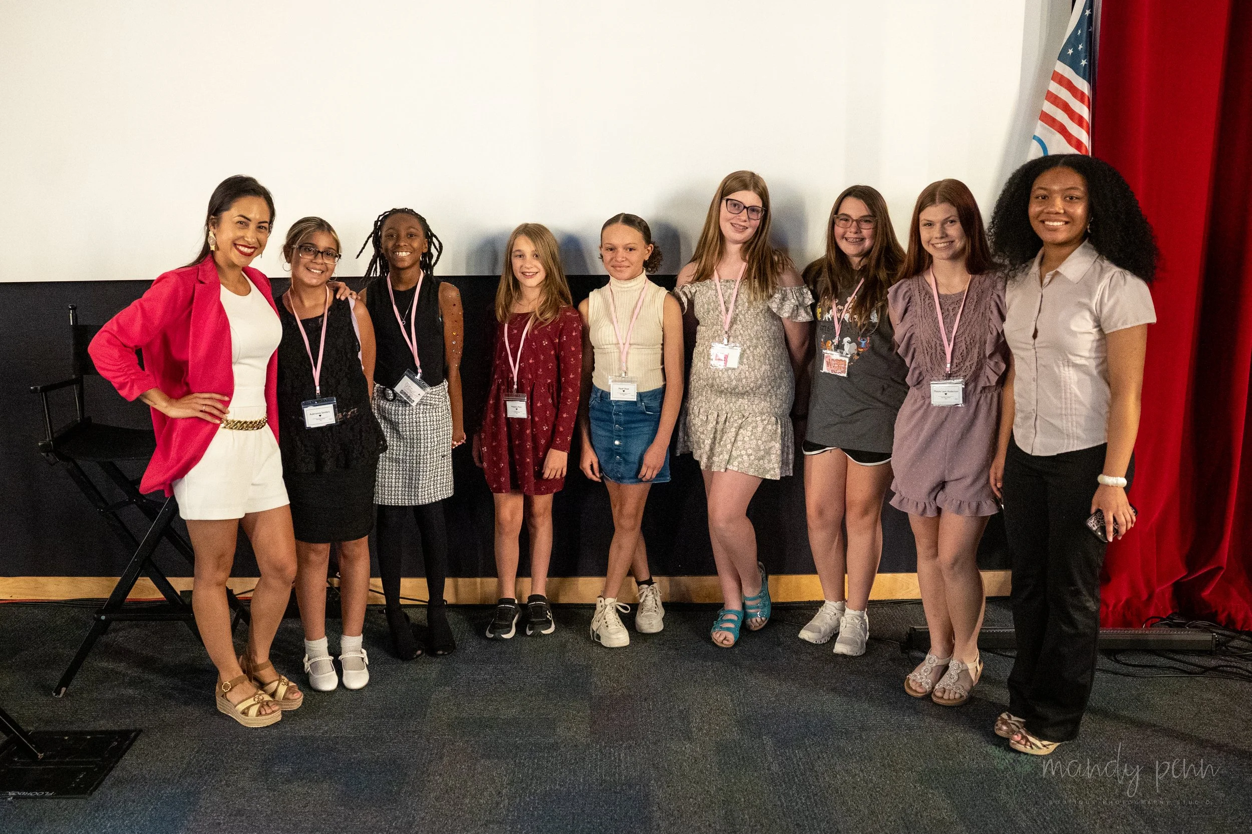 Group of girls and two female mentors posing on stage at a Boss Babe Academy leadership and confidence-building workshop.