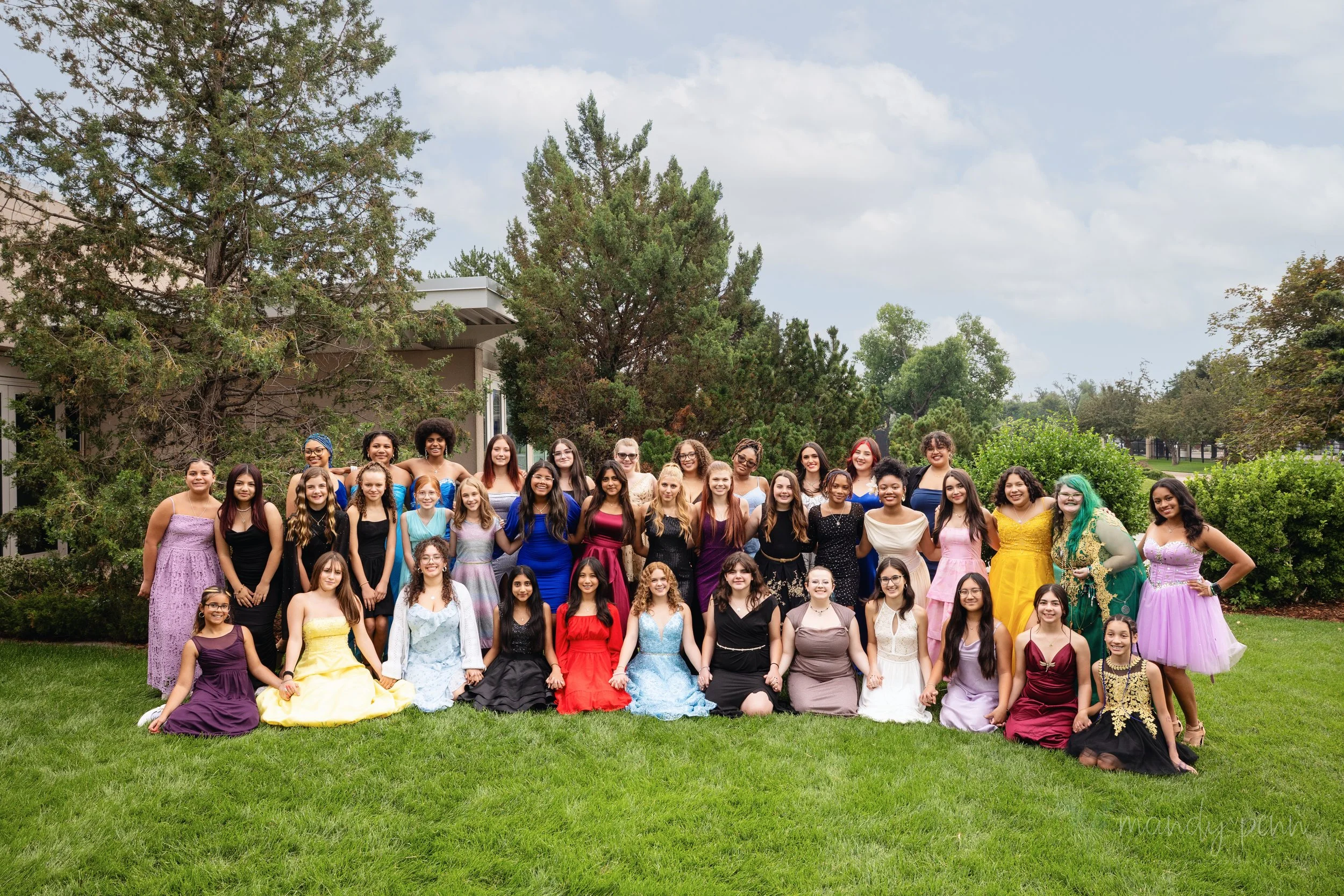Large group of girls and young women dressed in formal gowns posing outdoors at the Boss Babe Academy event in Colorado Springs.