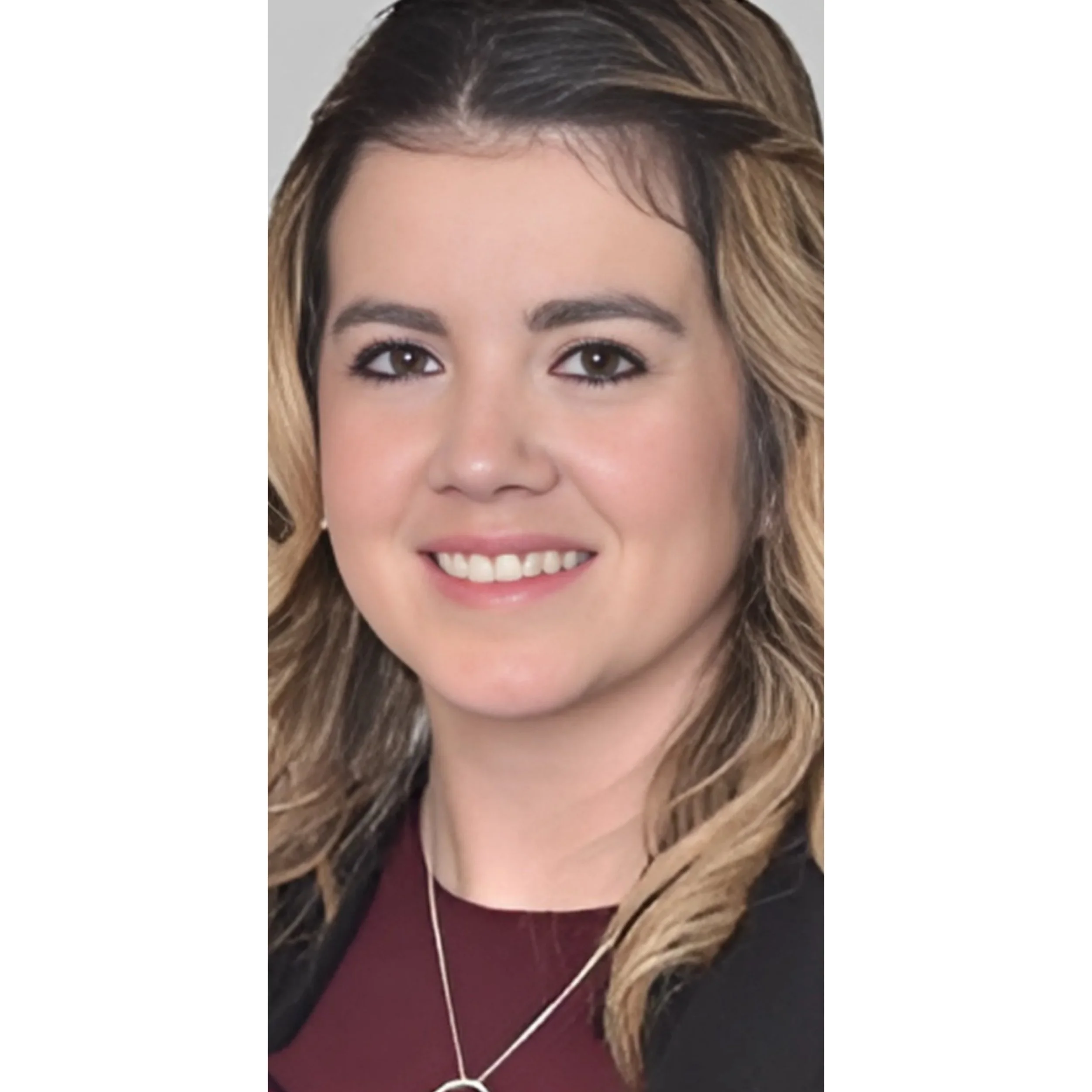A woman with shoulder-length wavy blonde hair, brown eyes, and a friendly smile, wearing a dark top and a silver necklace.