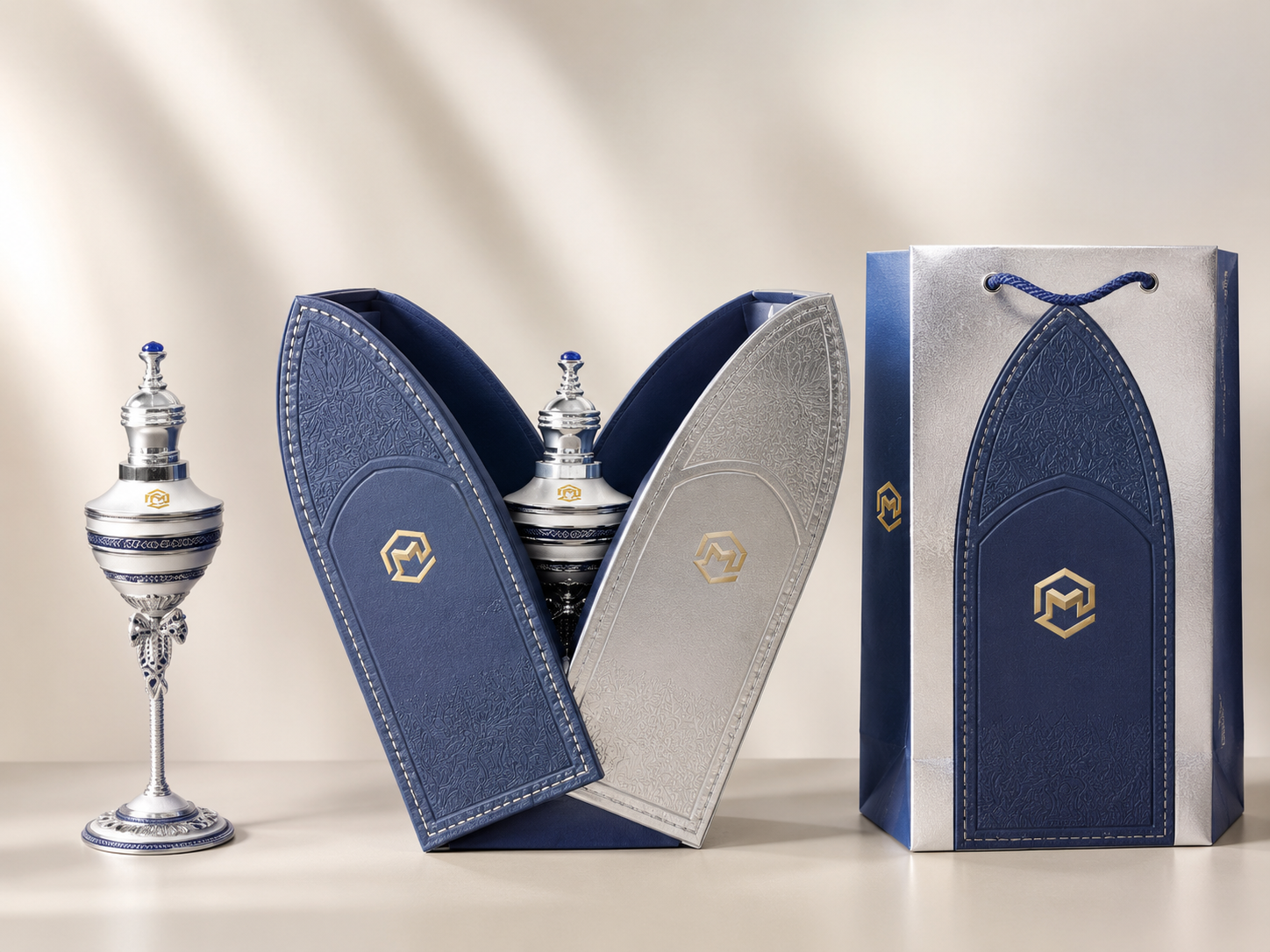 Silver and blue scent bottles inside decorative presentation boxes, with a matching gift bag to the right.