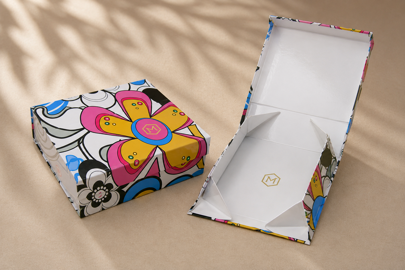 A colorful, decorated gift box with a floral pattern, open to reveal a blank interior, placed on a beige surface.