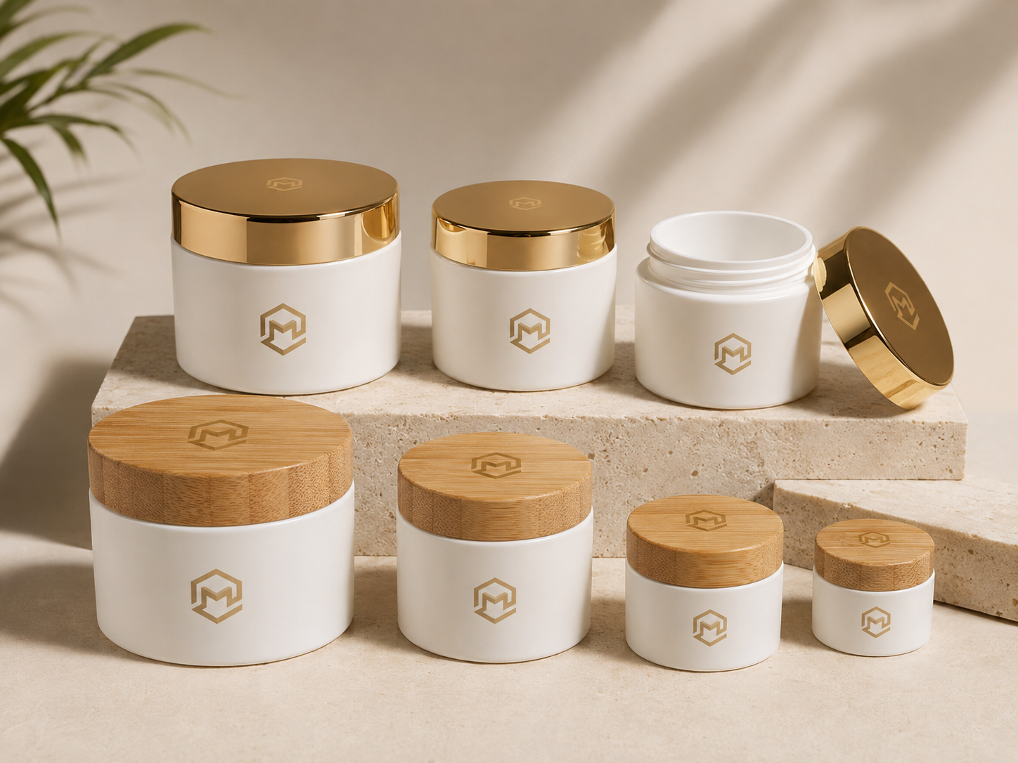 Collection of white cosmetic jars with gold lids and bamboo lids, featuring a geometric logo, displayed on a beige surface with neutral background.