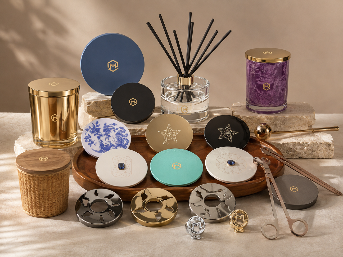 An arrangement of luxury candles, diffusers, decorative trays, and accessories on a beige surface with stone and wooden bases, featuring gold, black, gray, and blue accents.