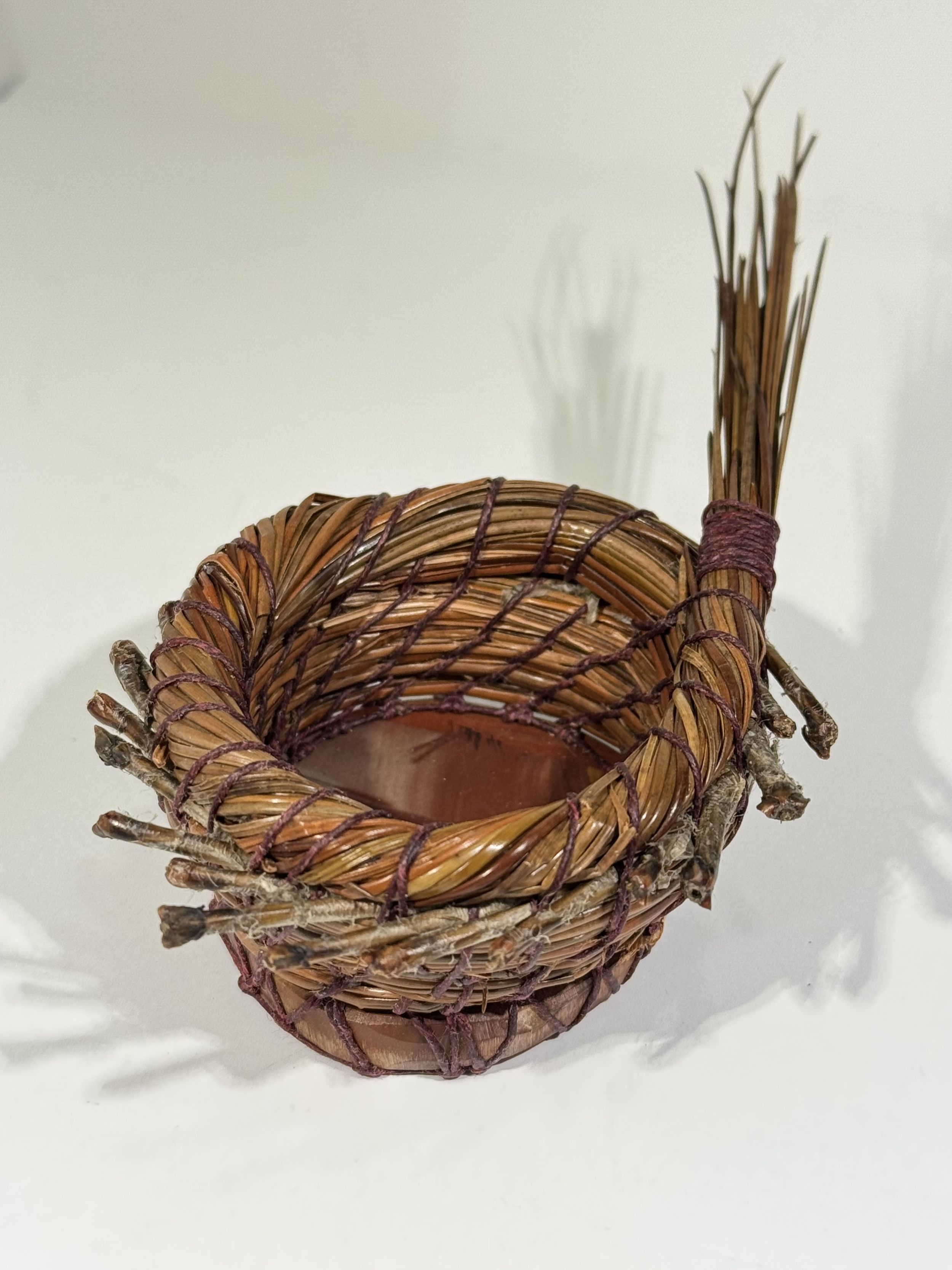No. 56: 2" round rock slice coil wrapped with glycerin treated 14" long pine needles . Process taught by Barbara Osborne (pineneedlerock.com) at the National Basketry Conference, Tacoma, WA, July 23-26, 2025).