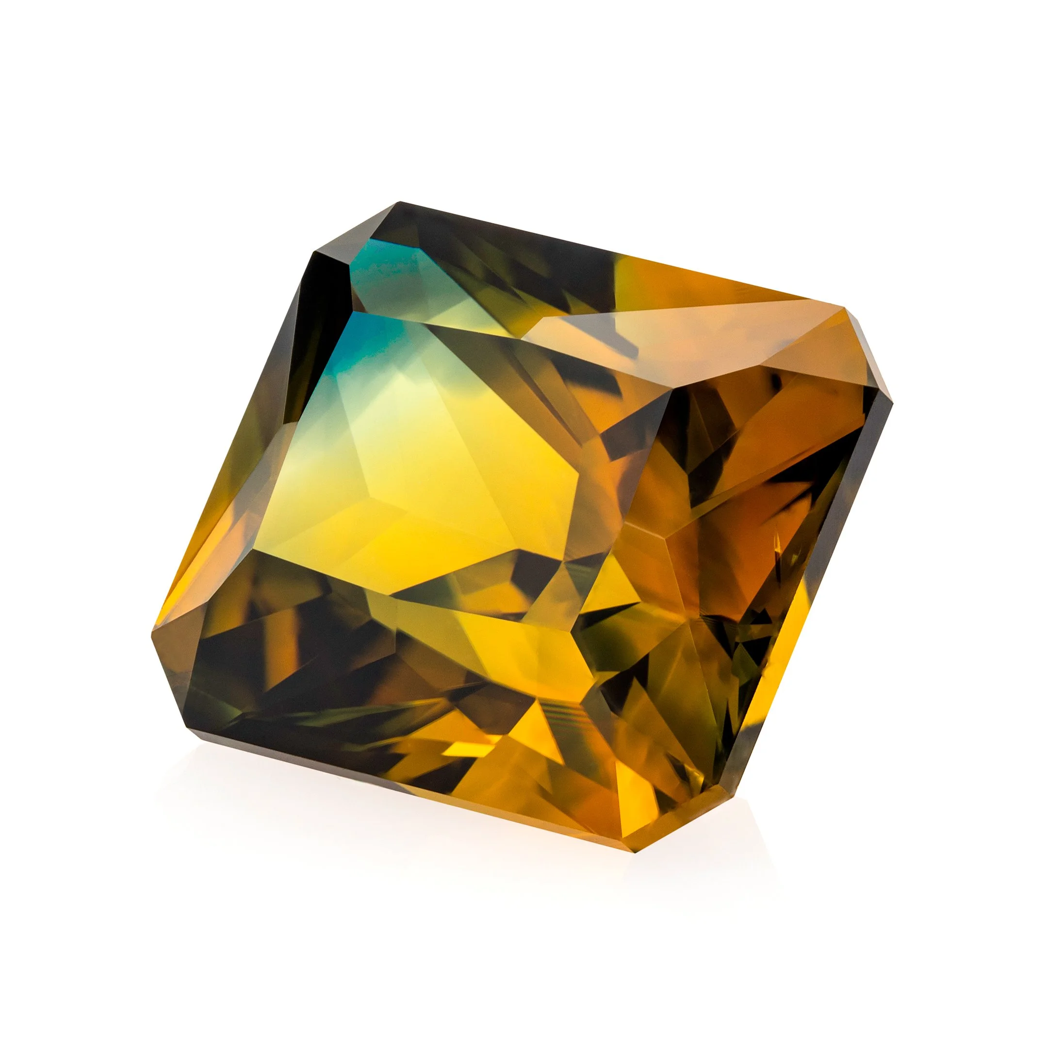 Macro photograph by Cesar Cueva of a faceted Australian parti sapphire, revealing angular planes and colour transitions from golden yellow and amber to green and turquoise.