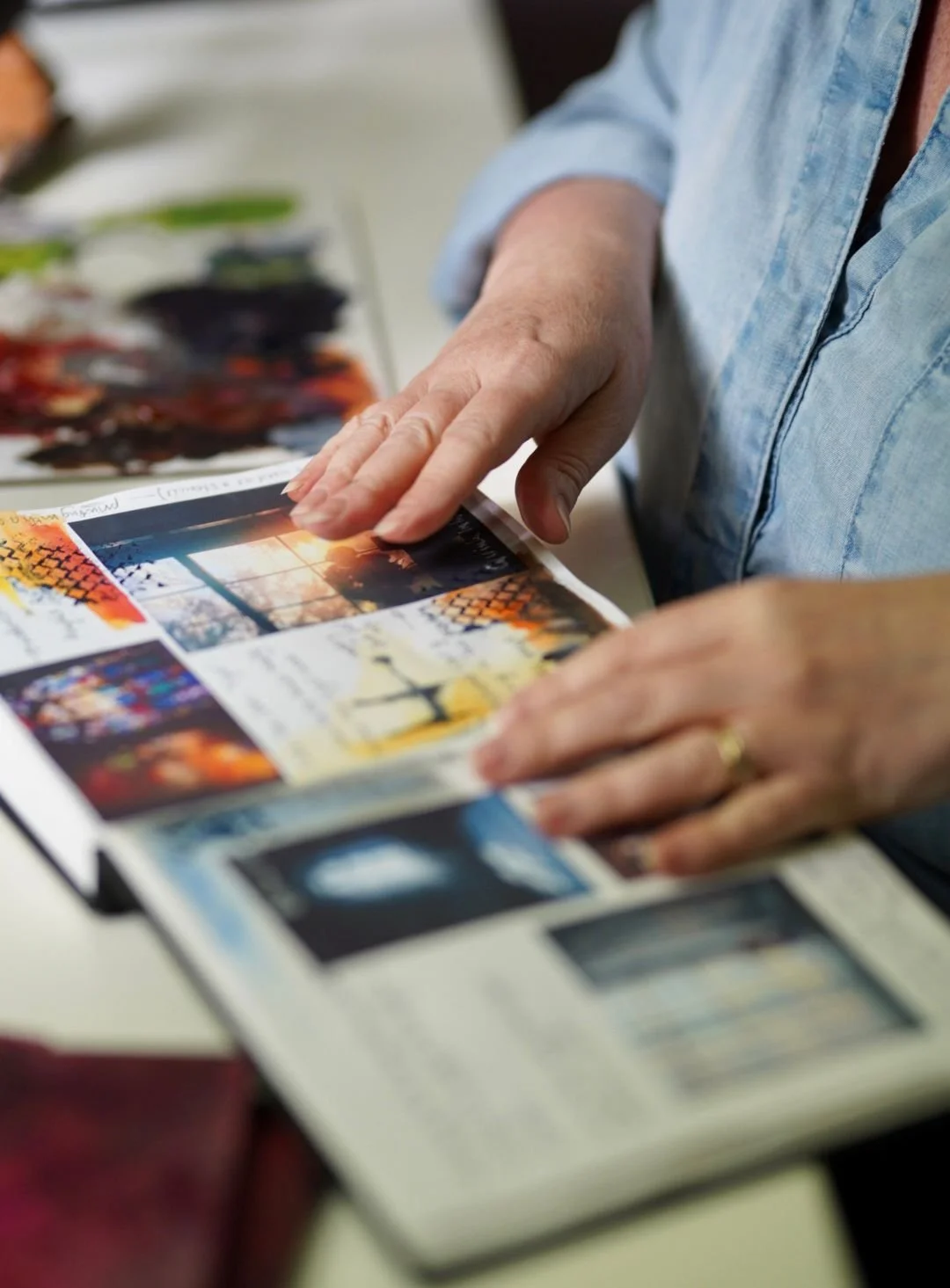 A person in a light blue shirt showing colorful images in a magazine or photo book.