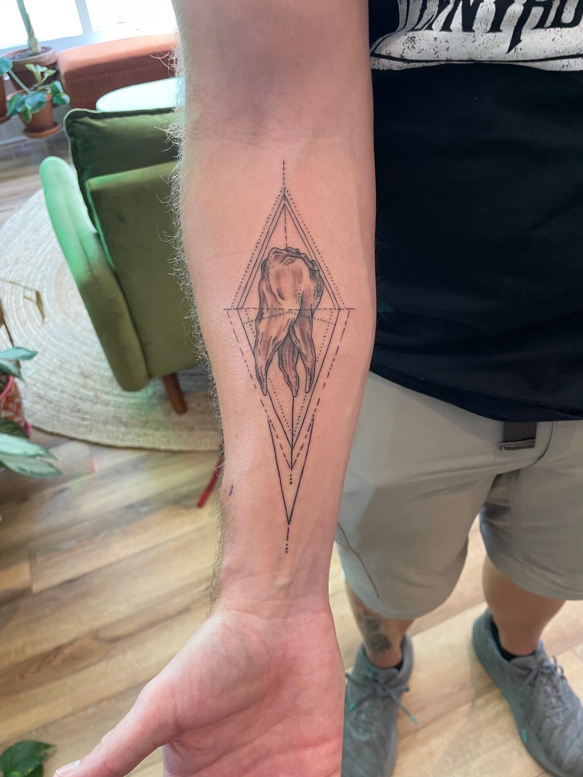 Tattoo of an abstract, organic shape within geometric lines on a person's forearm.